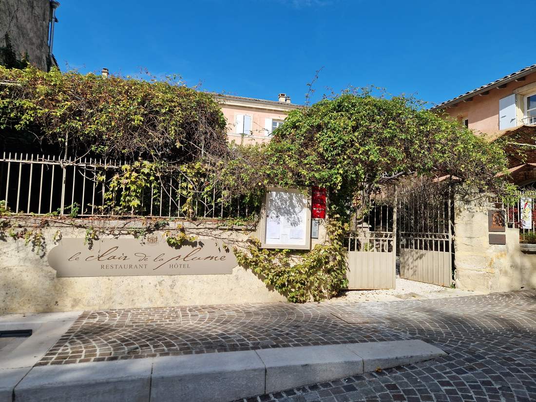 L'entrée de l'hôtel Le Clair de la Plume à Grignan, grille et façade sous la vigne vierge