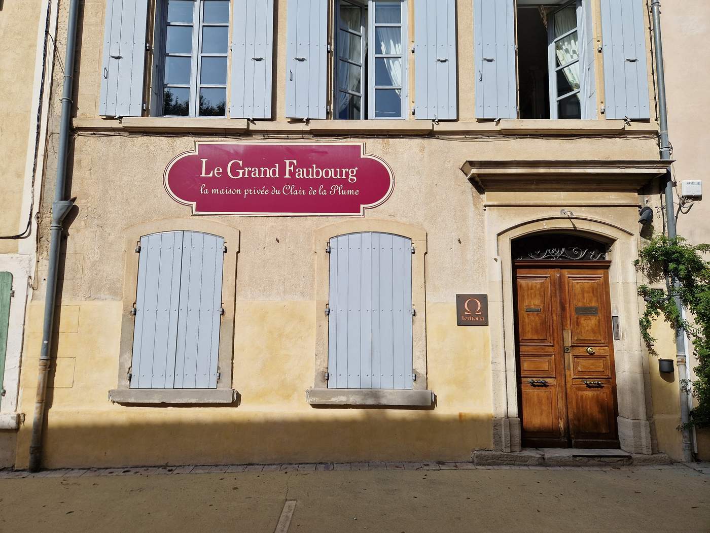 La façade du Grand Faubourg, maison du 19e siècle aux volets clairs, avec son enseigne bordeaux