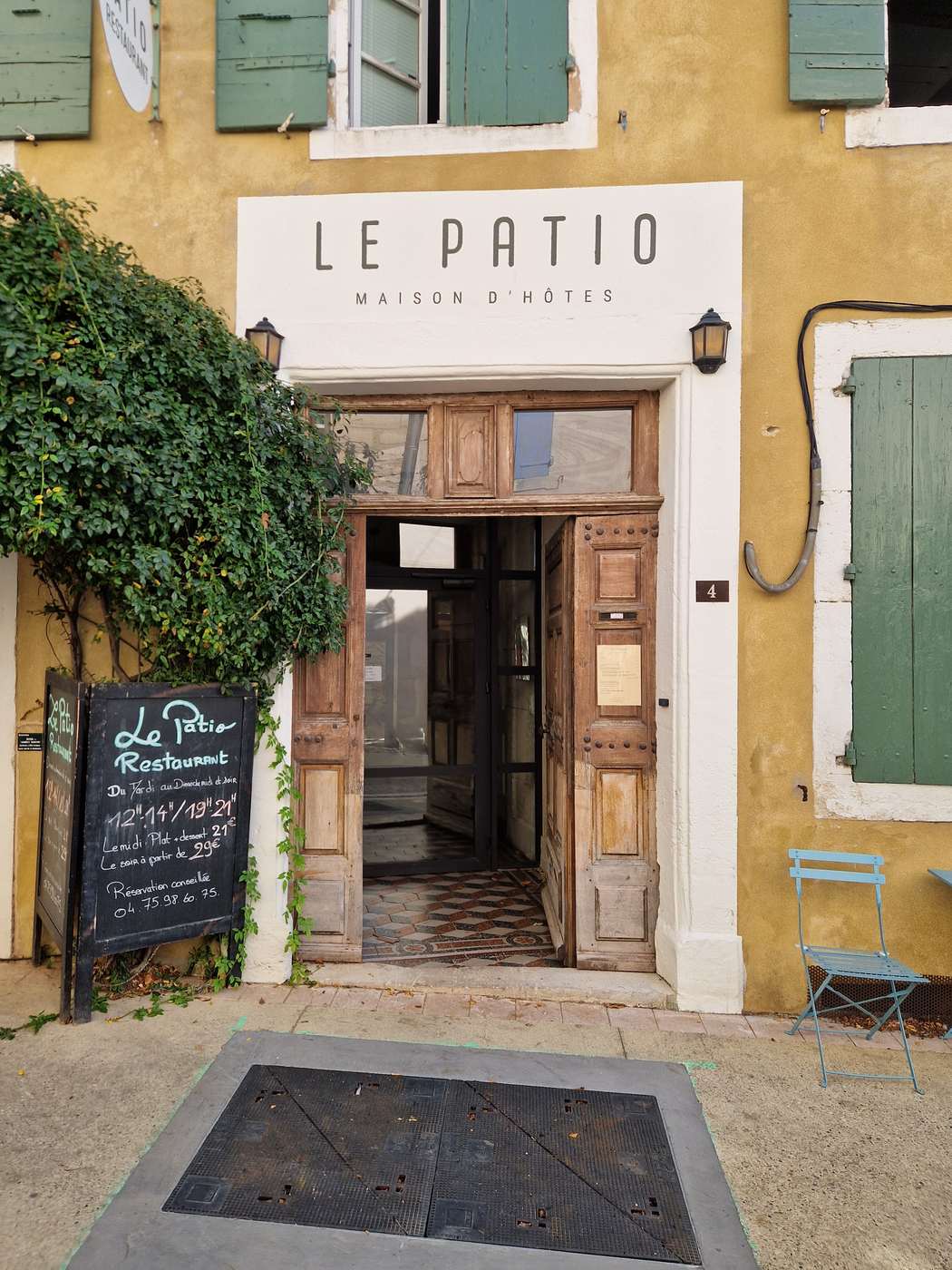 L'entrée de la maison d'hôtes Le Patio à Grignan, porte en bois ouverte sous une enseigne blanche