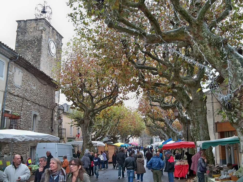 Le marché du ban des truffes de Richerenches sous les platanes, devant une tour à horloge