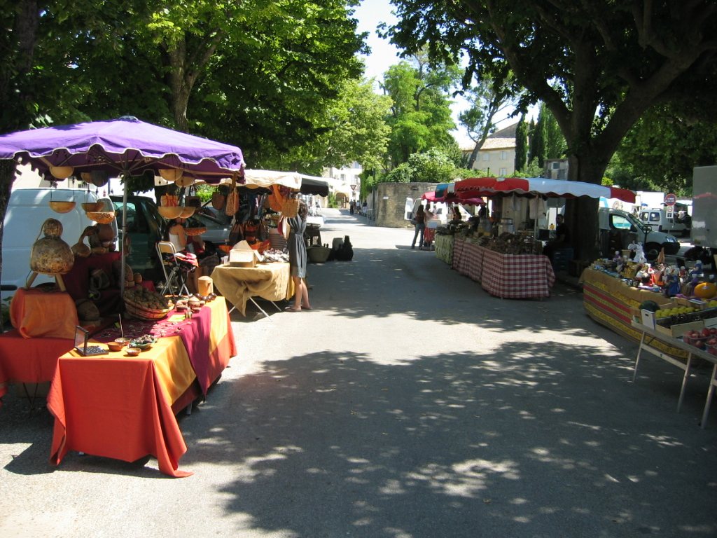 Étals du marché de Grignan sous les platanes, nappes colorées et parasols