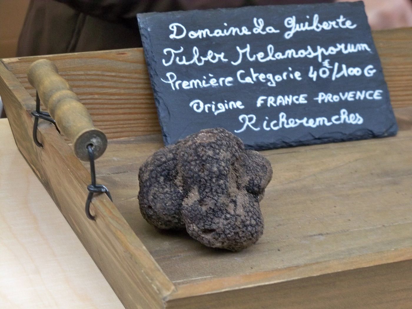 Une truffe noire Tuber melanosporum posée sur une planche de bois devant une ardoise
